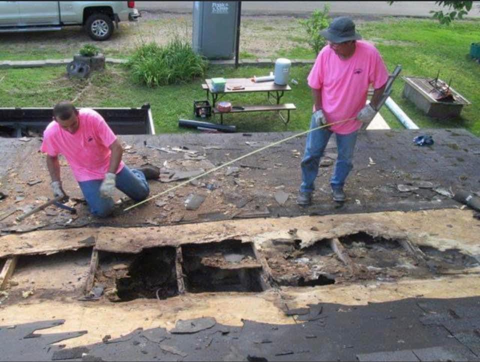 Two people measuring the dent in the roof